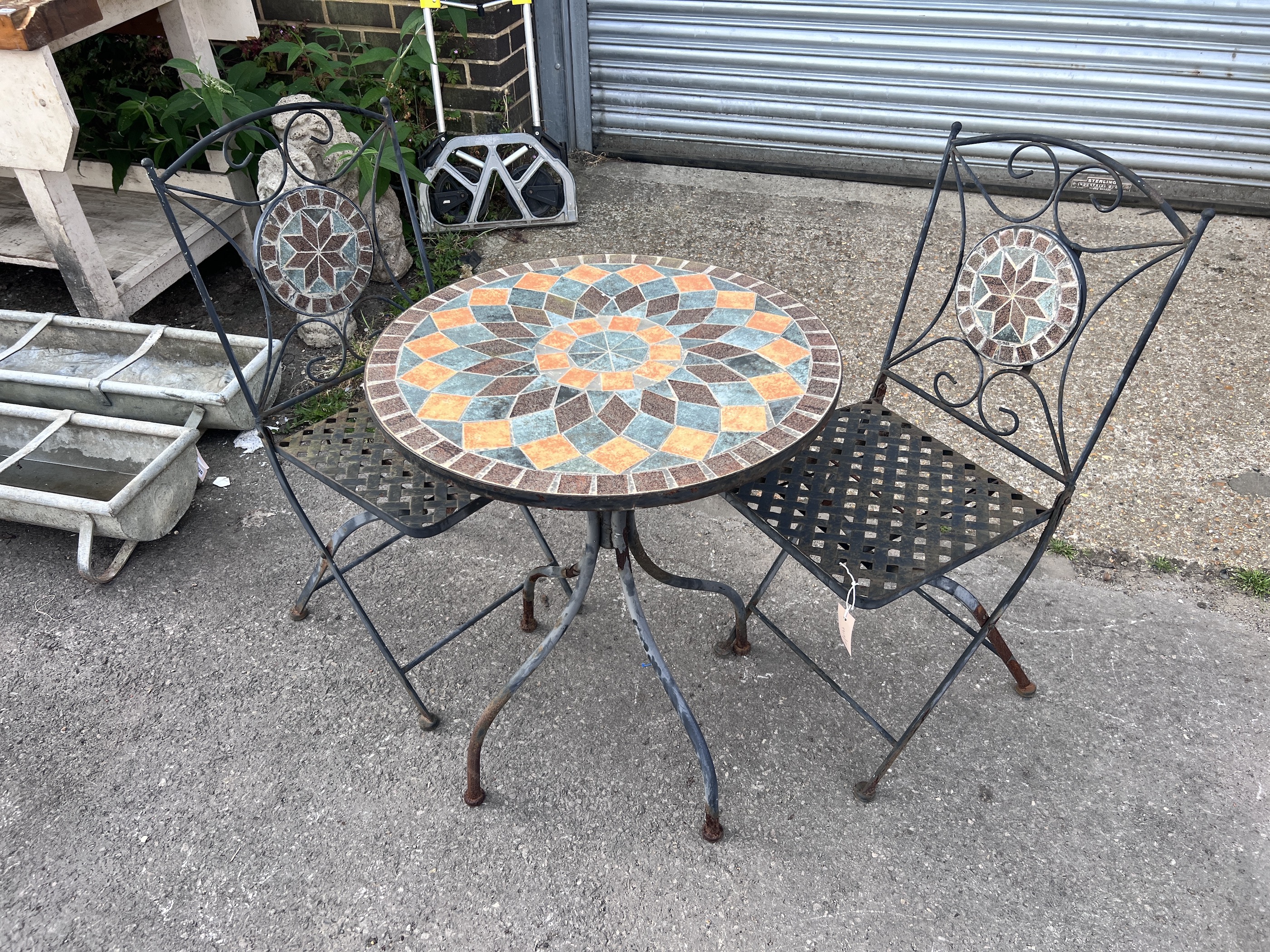 A circular mosaic topped garden table, diameter 60cm, height 73cm, and a pair of matching folding chairs